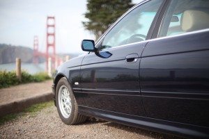 BMW 525i close-up with Golden Gate Bridge in the distance